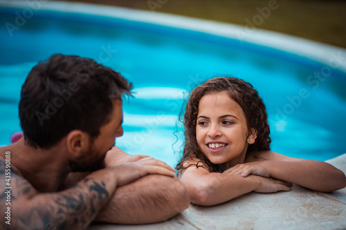 Father and daughter having talk in swimming pool. © liderina