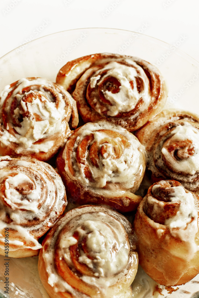 Close-up of fresh fragrant cinnabons with appetizing icing. Delicious homemade pastry or dessert at the bakery. Selective focus, top view