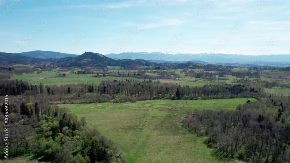 A view of the forested hills and the mountains covered with snow on the horizon. Drone flight over forests in the mountains. A view of the forested hills and the mountains covered with snow on the horizon. Drone flight over forests in the mountains.