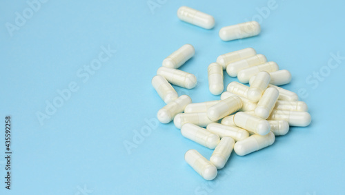 medical powder in white capsules on a blue background. Treatment pills, nutritional supplements