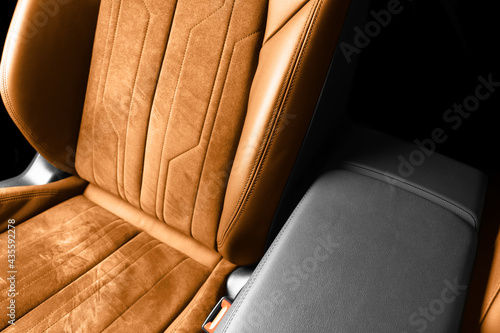 Modern luxury car brown leather with alcantara interior. Part of orange leather car seat details with white stitching. Interior of prestige car. Perforated leather seats isolated. Perforated leather.