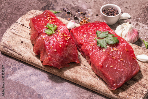 Raw beef steaks on a wooden cutting board