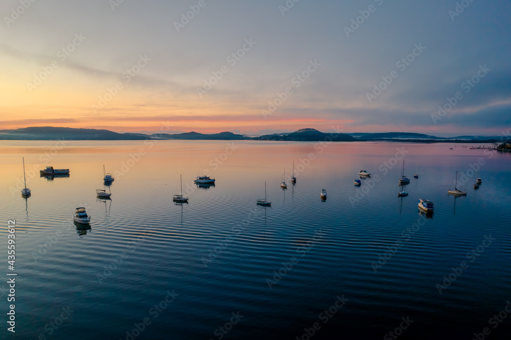 Sunrise waterscape with boats, light cloud and fog Sunrise waterscape with boats, light cloud and fog