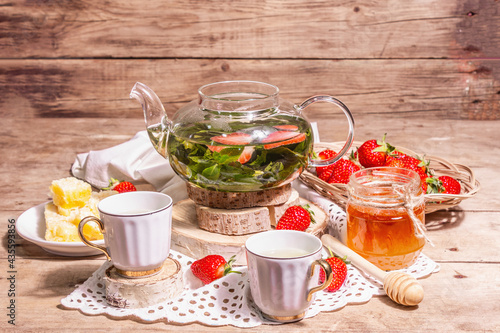 Teatime concept with aromatic mint tea, ripe strawberries, sweet honey