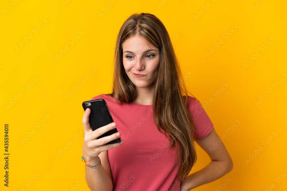 Young woman using mobile phone isolated on yellow background with sad expression Young woman using mobile phone isolated on yellow background with sad expression