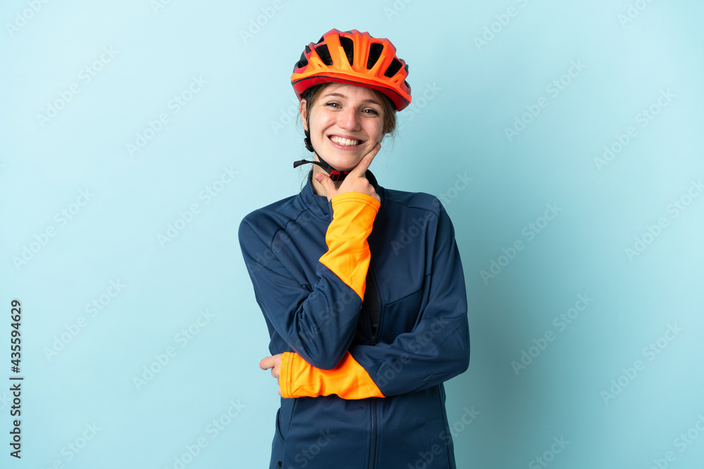 Young cyclist woman isolated on blue background happy and smiling - obrazy, fototapety, plakaty 