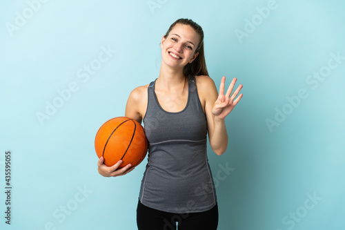 Young woman playing basketball isolated on blue background happy and counting four with fingers