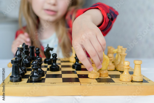 International Chess Day. A little girl learns chess pieces and learns to play chess.Table games. Family and children's leisure. Blurred background.