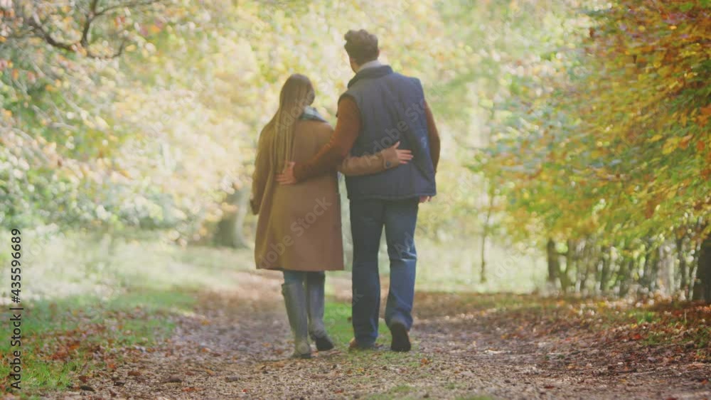 Rear view full length shot of loving mature couple walking along track in autumn countryside - shot in slow motion Rear view full length shot of loving mature couple walking along track in autumn countryside - shot in slow motion