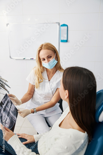 Cheerful stomatologist demonstrating dental radiograph to woman