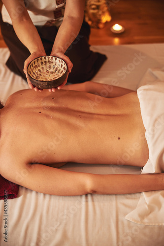 Beauty centre worker holding bowl with massage oil
