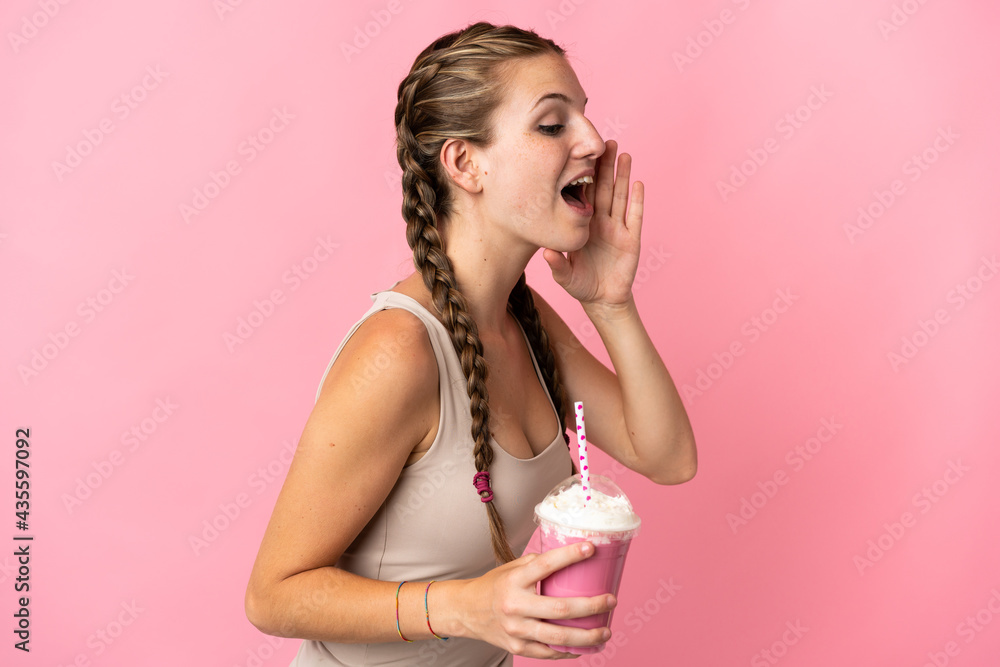 Young woman with strawberry milkshake isolated on pink background shouting with mouth wide open to the side Young woman with strawberry milkshake isolated on pink background shouting with mouth wide open to the side