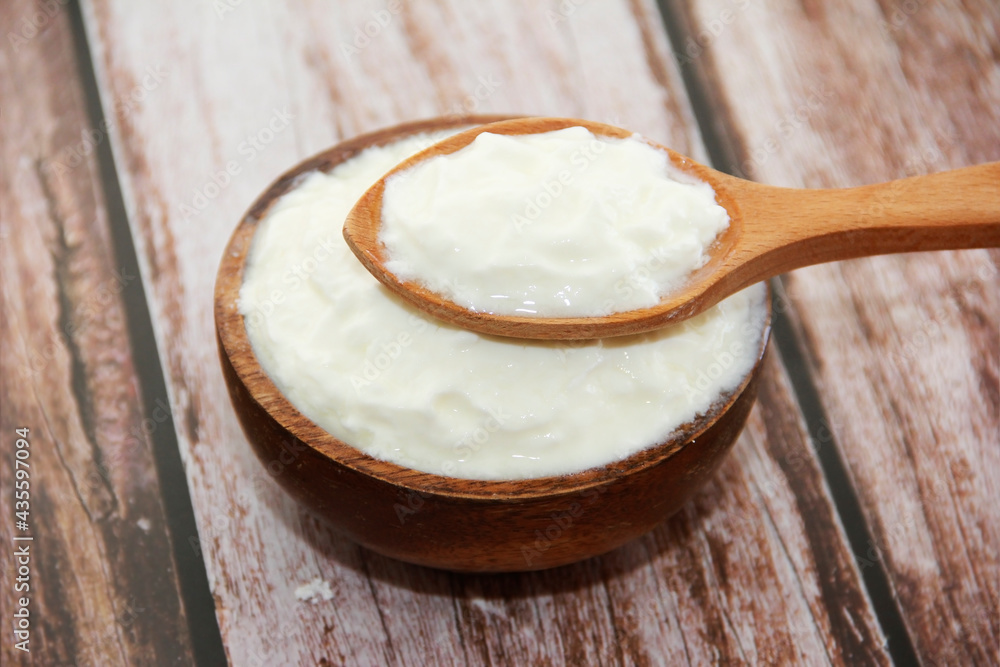 white milk yogurt in a wooden plate and spoon white milk yogurt in a wooden plate and spoon