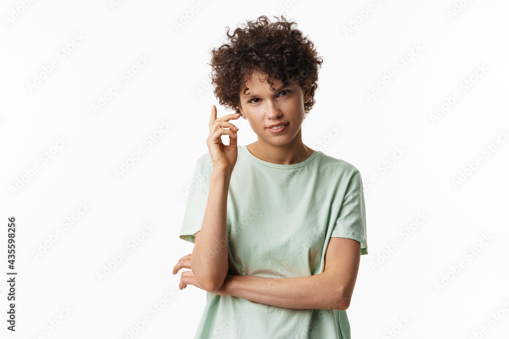 Young curly brunette woman gesturing and looking at camera Young curly brunette woman gesturing and looking at camera
