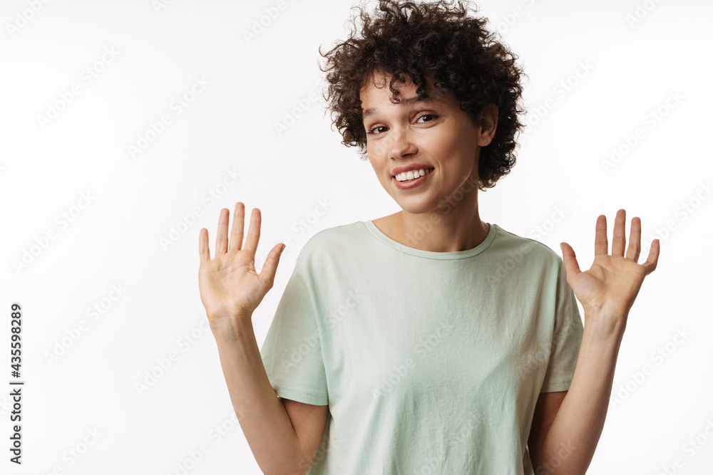 Young curly brunette woman gesturing and smiling at camera Young curly brunette woman gesturing and smiling at camera