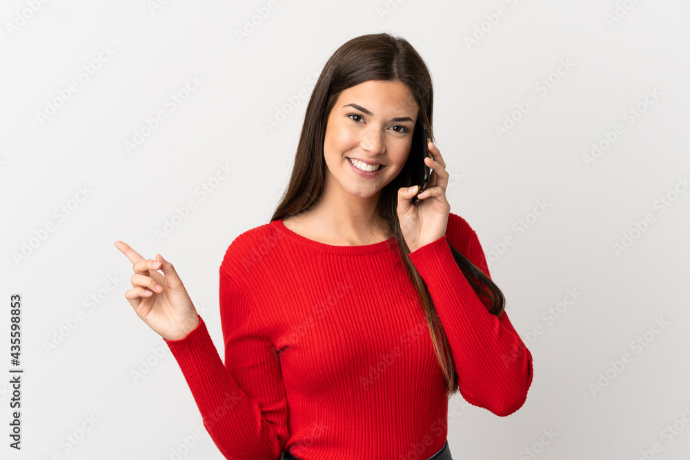 Teenager Brazilian girl using mobile phone over isolated white background pointing finger to the side Teenager Brazilian girl using mobile phone over isolated white background pointing finger to the side