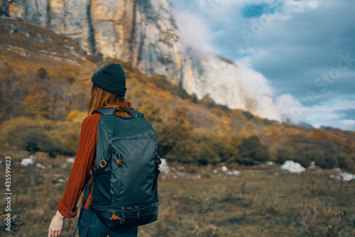 woman hiker with a backpack travels in the mountains outdoors in autumn fallen leaves