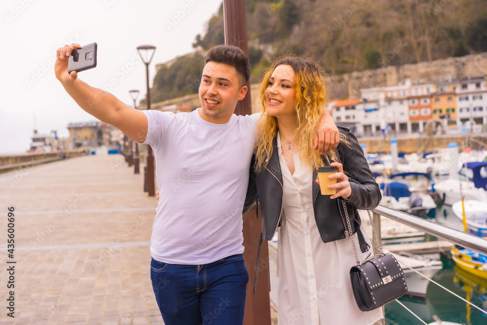Lifestyle of a couple sightseeing and enjoying the holidays. Strolling through a seaport and taking a photo Lifestyle of a couple sightseeing and enjoying the holidays. Strolling through a seaport and taking a photo