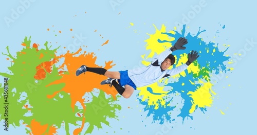 Composition of football goalkeeper over colourful splodges on blue background photo