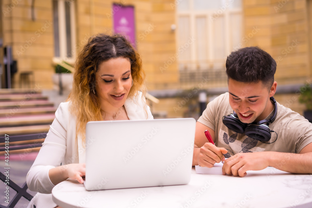 Young entrepreneurs doing teamwork. Working on the internet with the computer on a terrace of a bar Young entrepreneurs doing teamwork. Working on the internet with the computer on a terrace of a bar