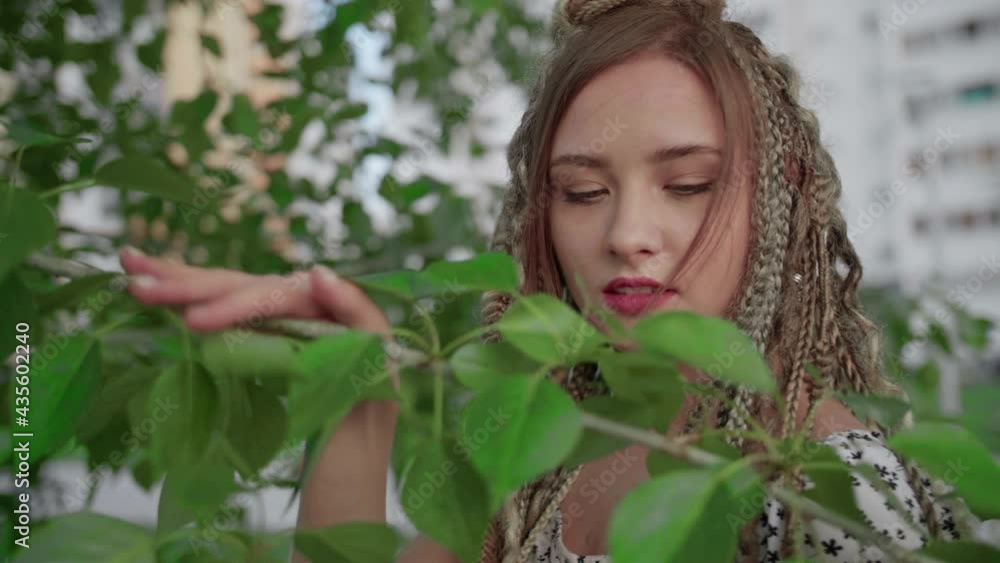 A cute girl with dreadlocks poses by a tree with leaves A cute girl with dreadlocks poses by a tree with leaves