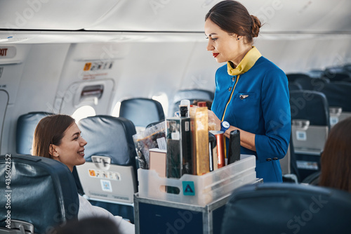 Foto Woman on plane addressing flight attendant with food trolley