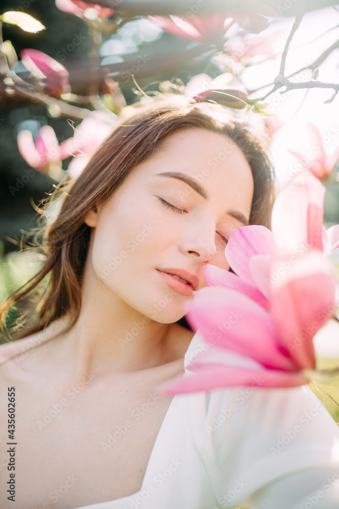 Woman enjoys and sniffs magnolia flowers in spring garden. Woman enjoys and sniffs magnolia flowers in spring garden.