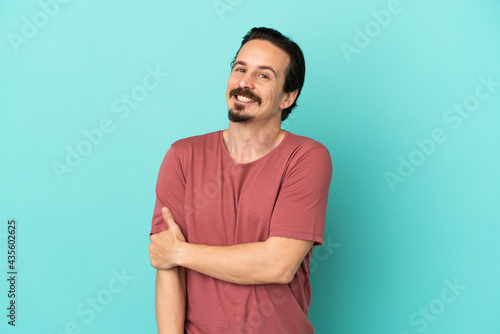 Young caucasian man isolated on blue background laughing