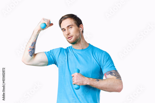 man with dumbbells pumped up arm muscles smile model tattoo blue t-shirt