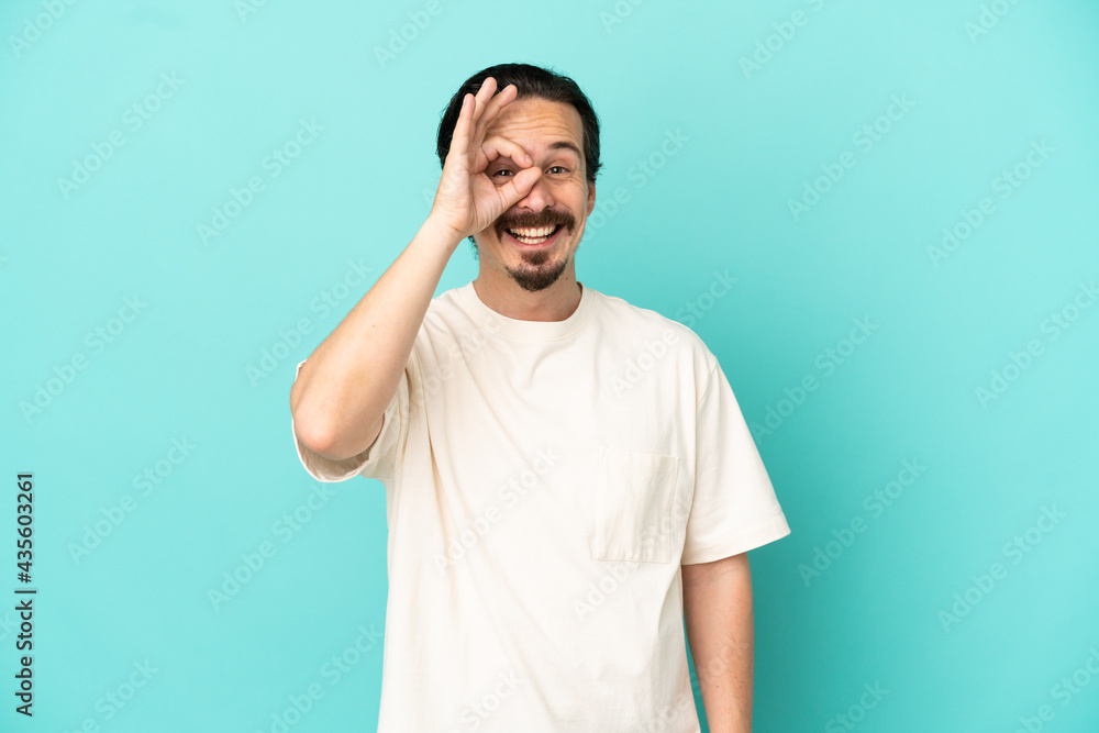 Young caucasian man isolated on blue background showing ok sign with fingers Young caucasian man isolated on blue background showing ok sign with fingers
