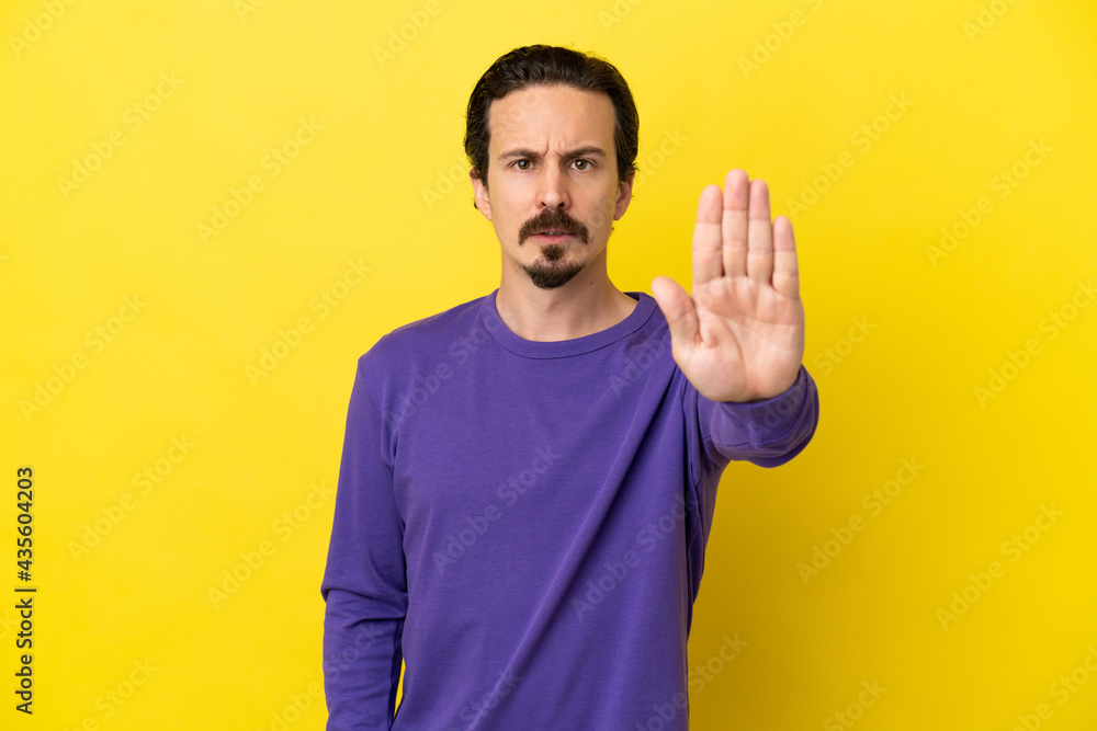 Young caucasian man isolated on yellow background making stop gesture Young caucasian man isolated on yellow background making stop gesture