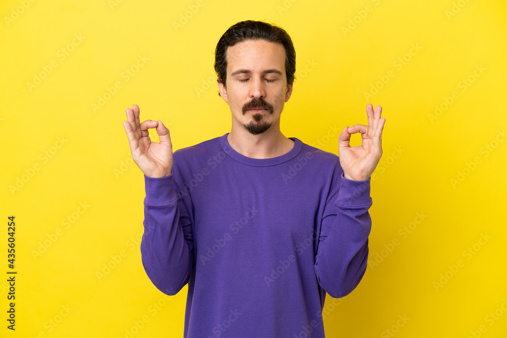 Young caucasian man isolated on yellow background in zen pose Young caucasian man isolated on yellow background in zen pose