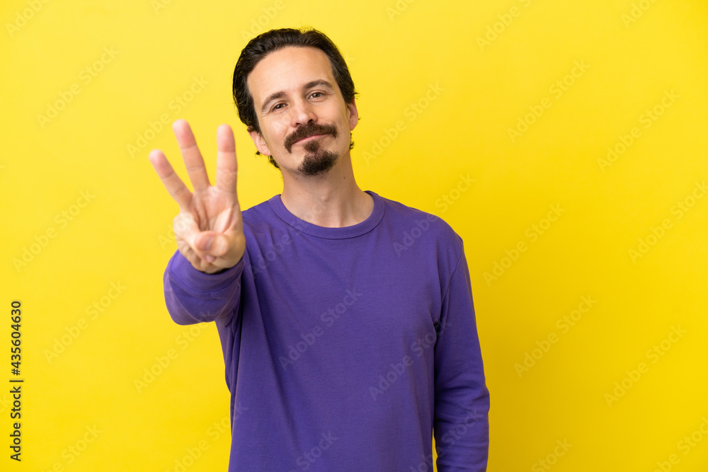 Young caucasian man isolated on yellow background happy and counting three with fingers Young caucasian man isolated on yellow background happy and counting three with fingers