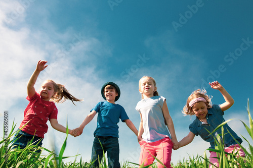 A group of happy children of boys and girls run in the Park on the grass on a Sunny summer day . The concept of ethnic friendship, peace, kindness, childhood