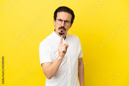 Young caucasian man isolated on yellow background frustrated and pointing to the front