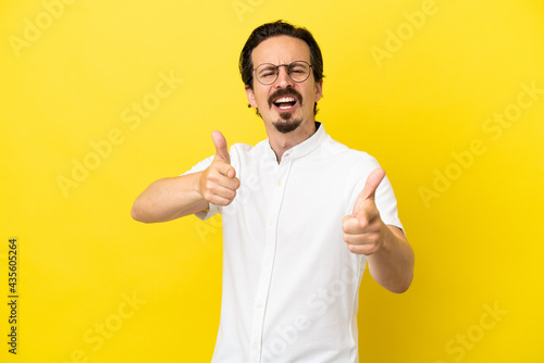 Young caucasian man isolated on yellow background pointing to the front and smiling