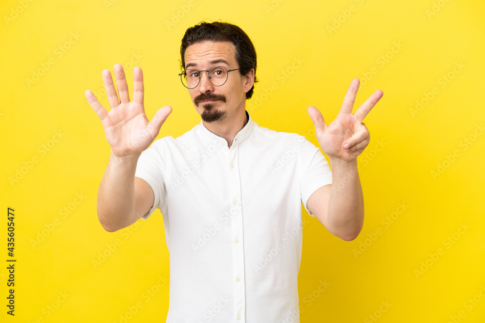 Young caucasian man isolated on yellow background counting eight with fingers Young caucasian man isolated on yellow background counting eight with fingers