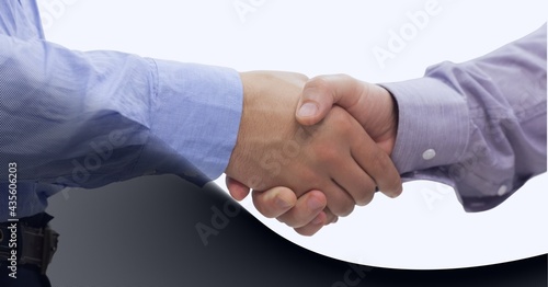 Mid section of two businessman shaking hands against technology background