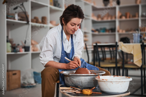 Pottery artist making use of loop instrument for bowl creation