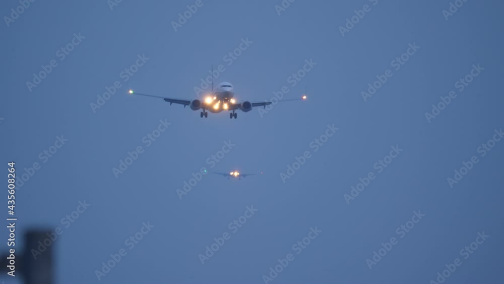 Passenger plane approaching airport for landing, front view. One more passenger liner seen on background. Bright headlights and blinking sidelights on wings Passenger plane approaching airport for landing, front view. One more passenger liner seen on background. Bright headlights and blinking sidelights on wings