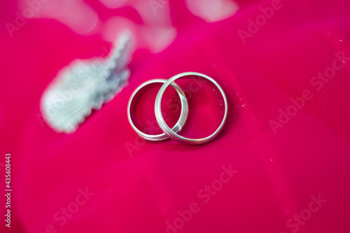 Two platinum engagement or wedding rings isolated on pink background. Symbol for marriage, love, relationships, proposals, valentine's day, engagement etc...