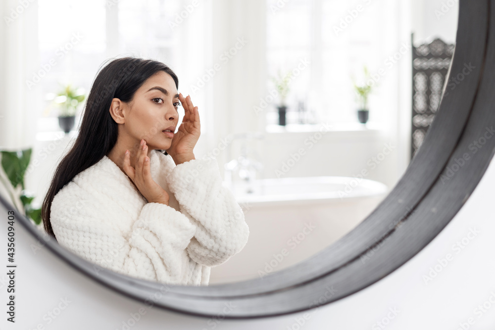 Young asian woman looking at mirror, checking skin Young asian woman looking at mirror, checking skin