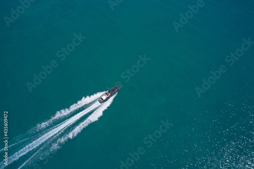 Large white boat fast movement on blue water aerial view. Motor performance boat in the sea. Drone view of a boat sailing. Top view of a white boat sailing to the blue sea.