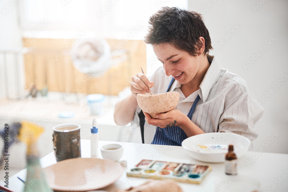 Satisfied ceramic goods designer making a painting in pottery bowl Satisfied ceramic goods designer making a painting in pottery bowl