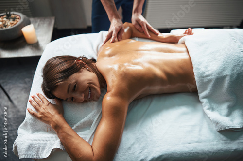 Pretty Caucasian female getting professional massage on her body in spa salon