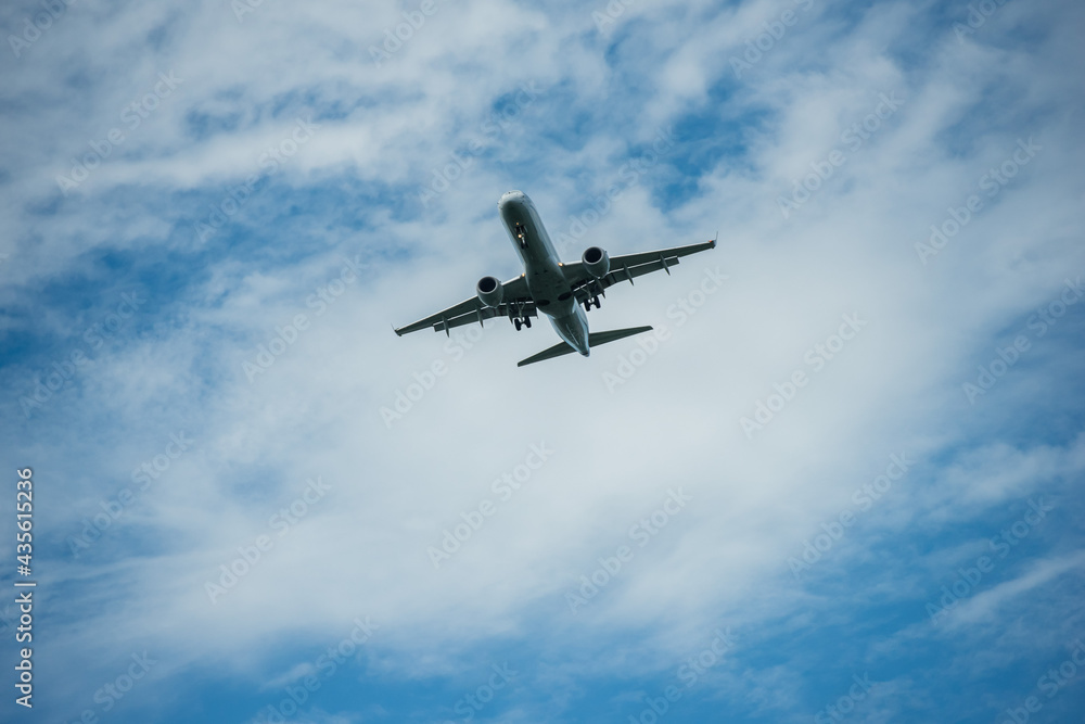 Airplane flying through blue sky with puffy clouds.