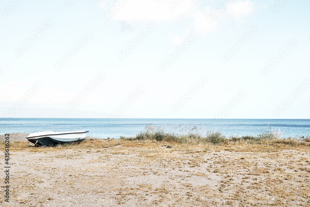 White boat on the beach. Tourist season on the mediterranean sea. Sicily. Ionian sea. Minimalism in nature. White boat on the beach. Tourist season on the mediterranean sea. Sicily. Ionian sea. Minimalism in nature.