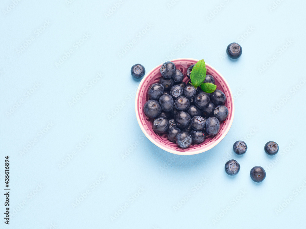 Bowl of fresh blueberries on a blue background Bowl of fresh blueberries on a blue background