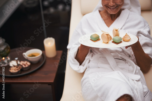 Charming business female sitting on deck chair while showing at the photo camera tasty dessert in wellness center
