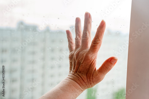 The old woman's hand touched the window with rain